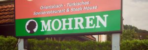 A sign outside a restaurant in Hohenems advertises that they serve Mohren. The beer's name and logo have racial connotations. 